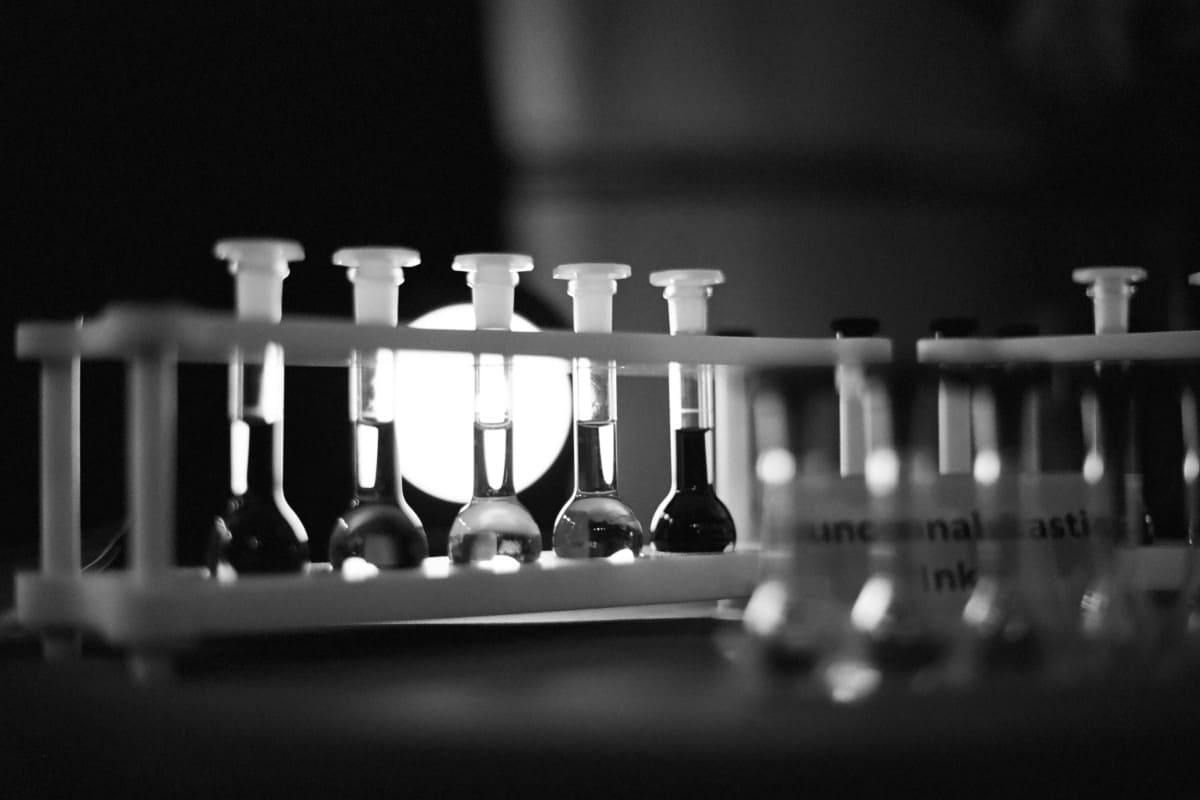A black and white photo of several test tubes on a table, taken during the INOGOV Workshop on climate change policy.