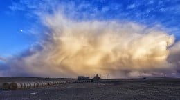 A large cloud over a field of hay bales amidst discussions on international cooperative initiatives.